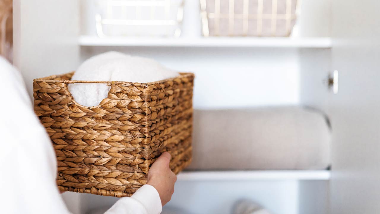 Woman organizing clothes on shelves in white opened wardrobe