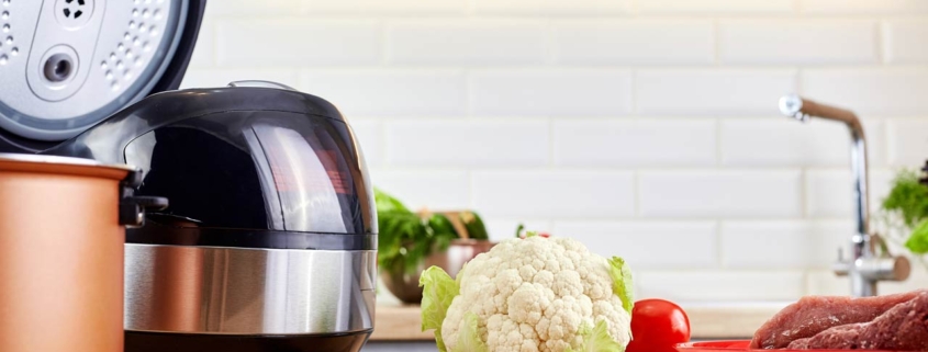 Modern pot with multicooker and products on kitchen table