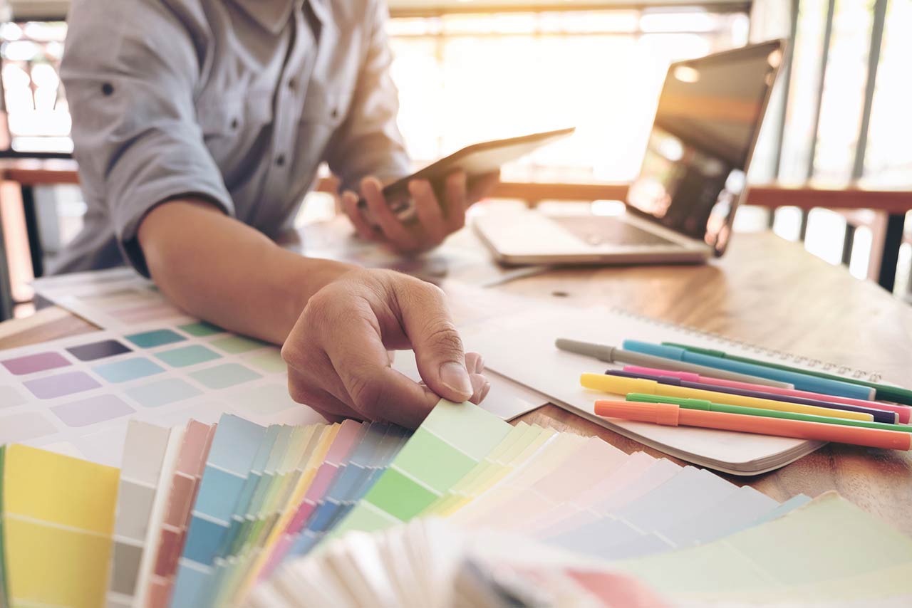 Man with laptop and paint swatches to select a new color