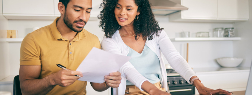 Couple reviewing financial documents at a kitchen counter