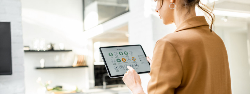 woman controlling smart home devices using a digital tablet with launched application in the white living room