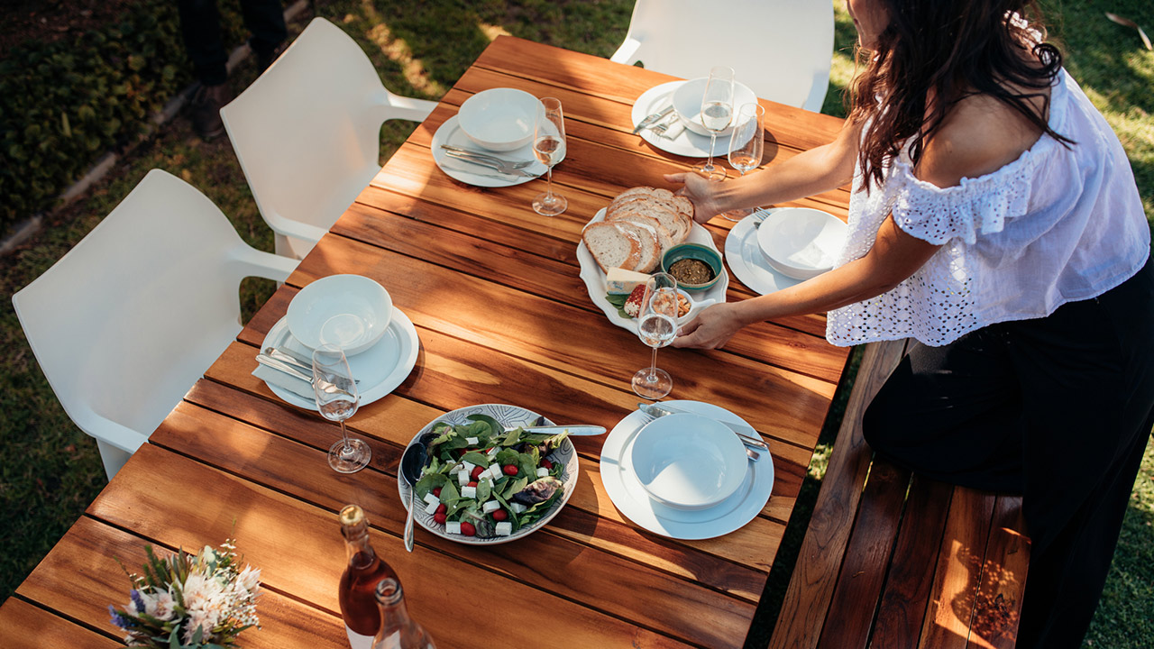 Top view of woman setting food on wooden table for housewarming party.