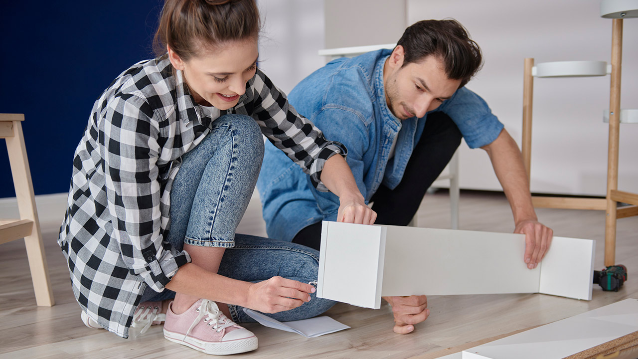 couple installing bookshelf for new house stock photo