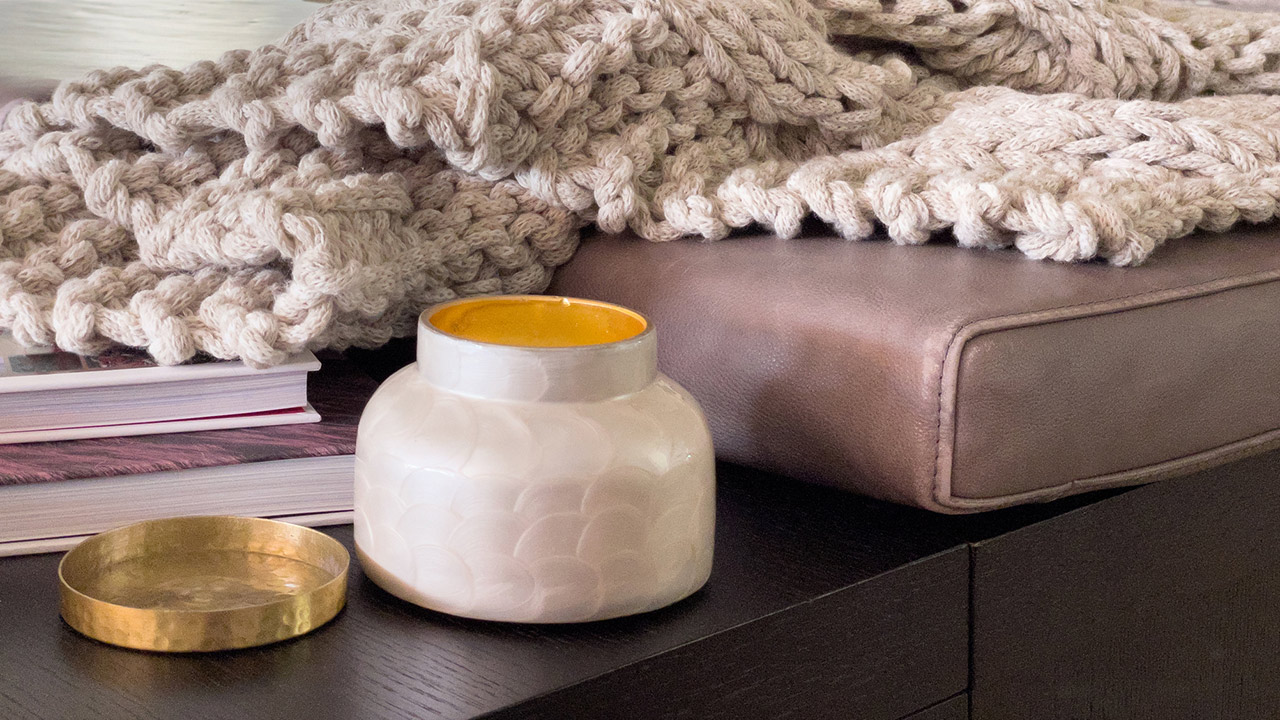 Warm comfy living room setting with candle and chunky afgan with thick gray yarn stock photo